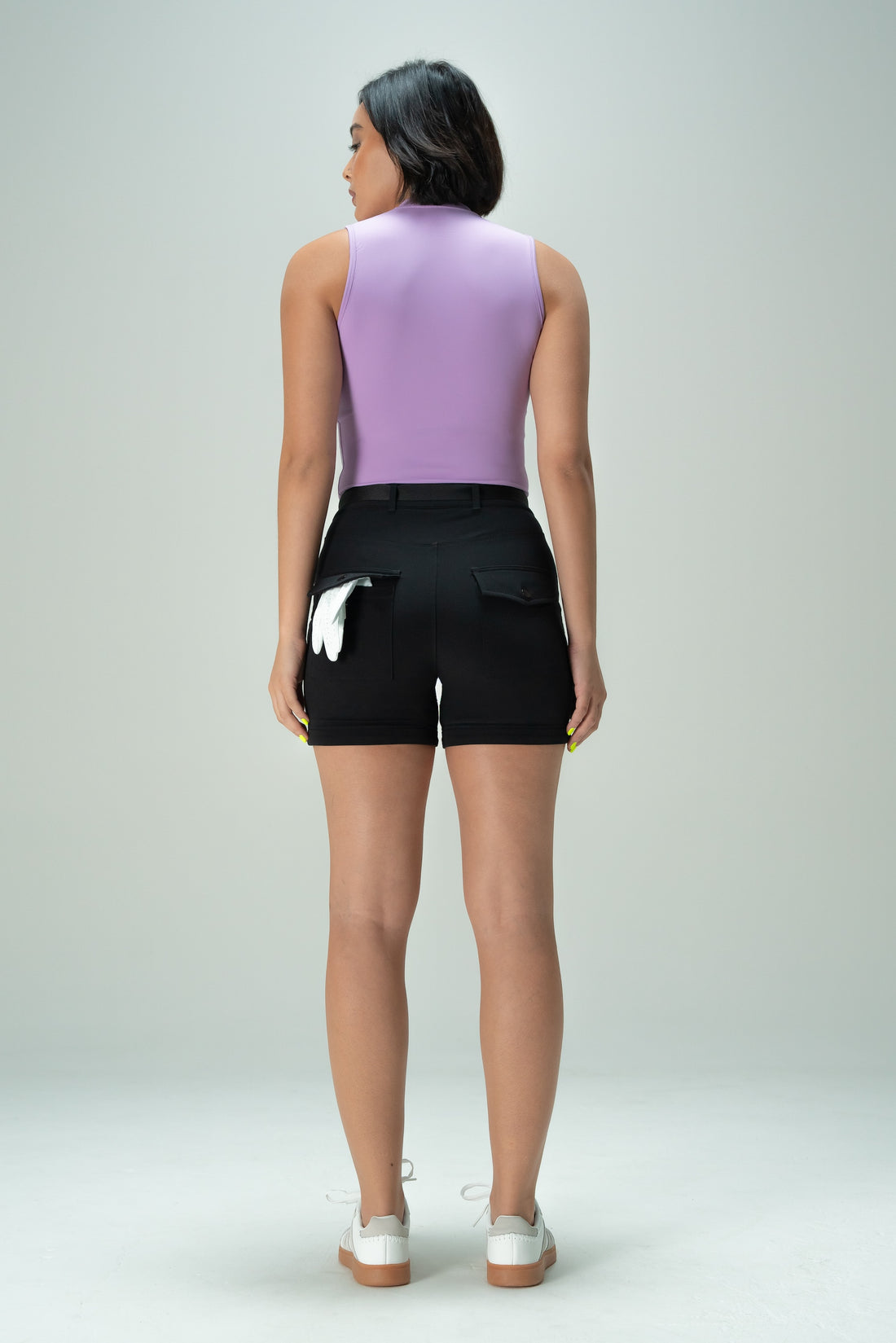 Person wearing a purple sleeveless top and black shorts on a plain background