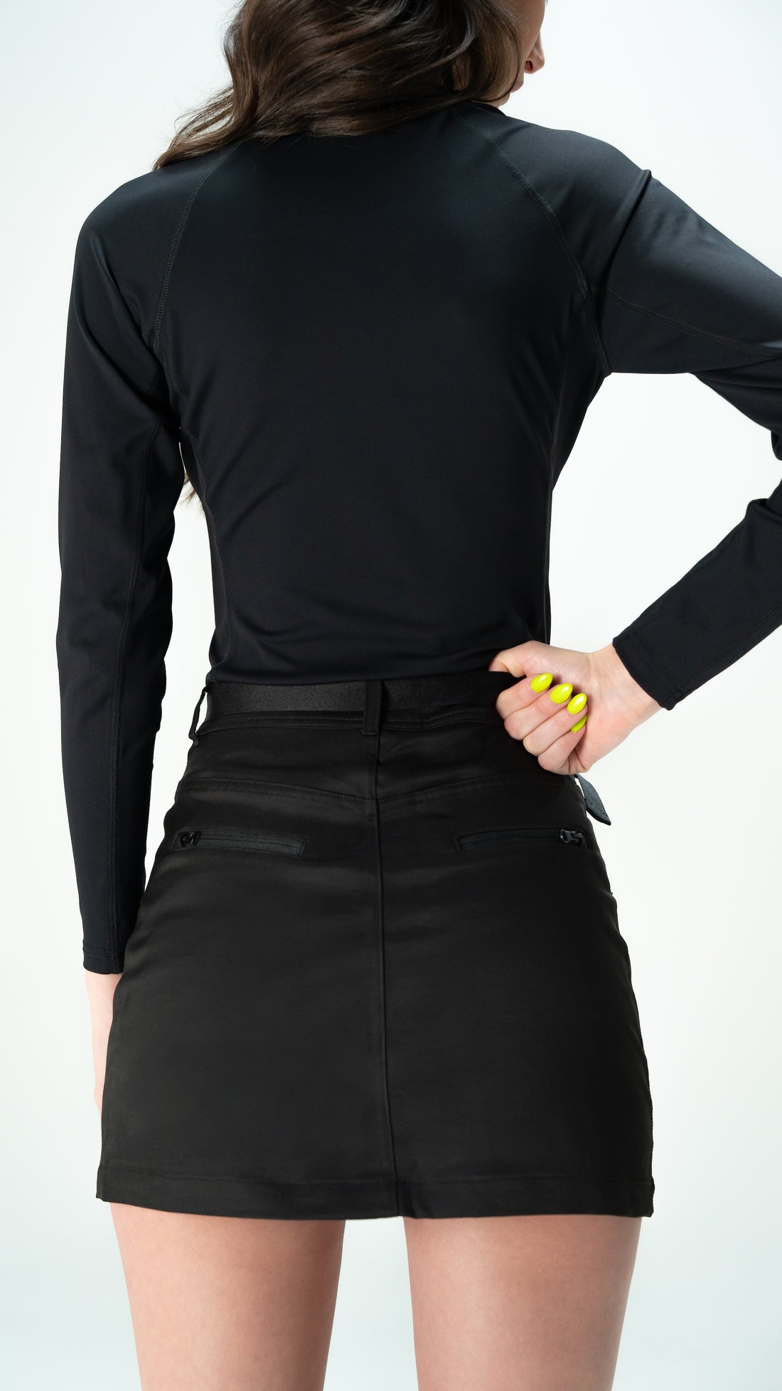 Person wearing a black long-sleeve top and black skirt on a white background