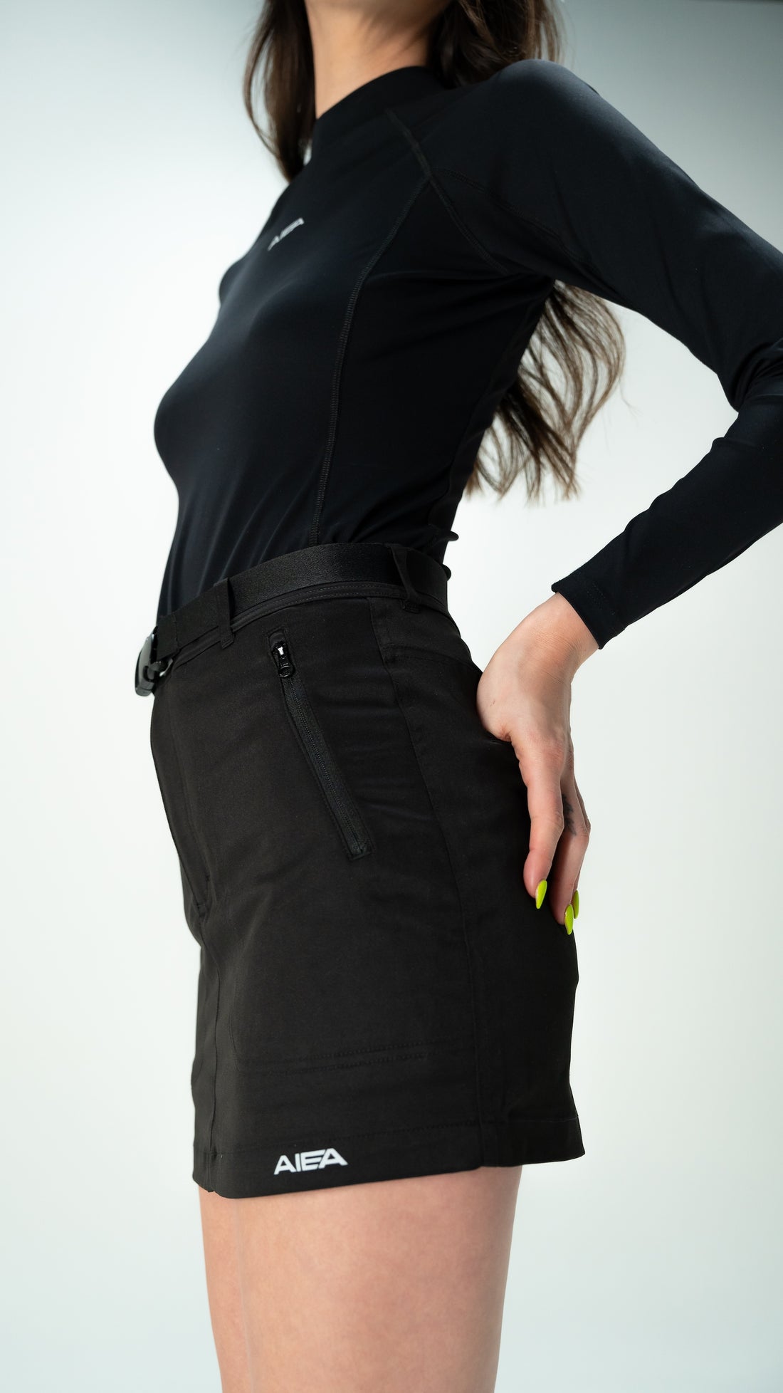 Person wearing a black outfit with a belt and 'AIEA' branding on a white background